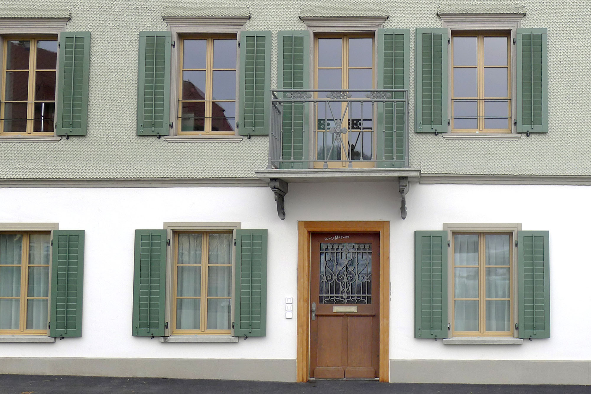 Ausschnitt Fassade Nordwest Brückenhaus; in der Bildmitte Hauseingang im Sockelgeschoss darüber Balkon und Fassade mit Schindelschirm